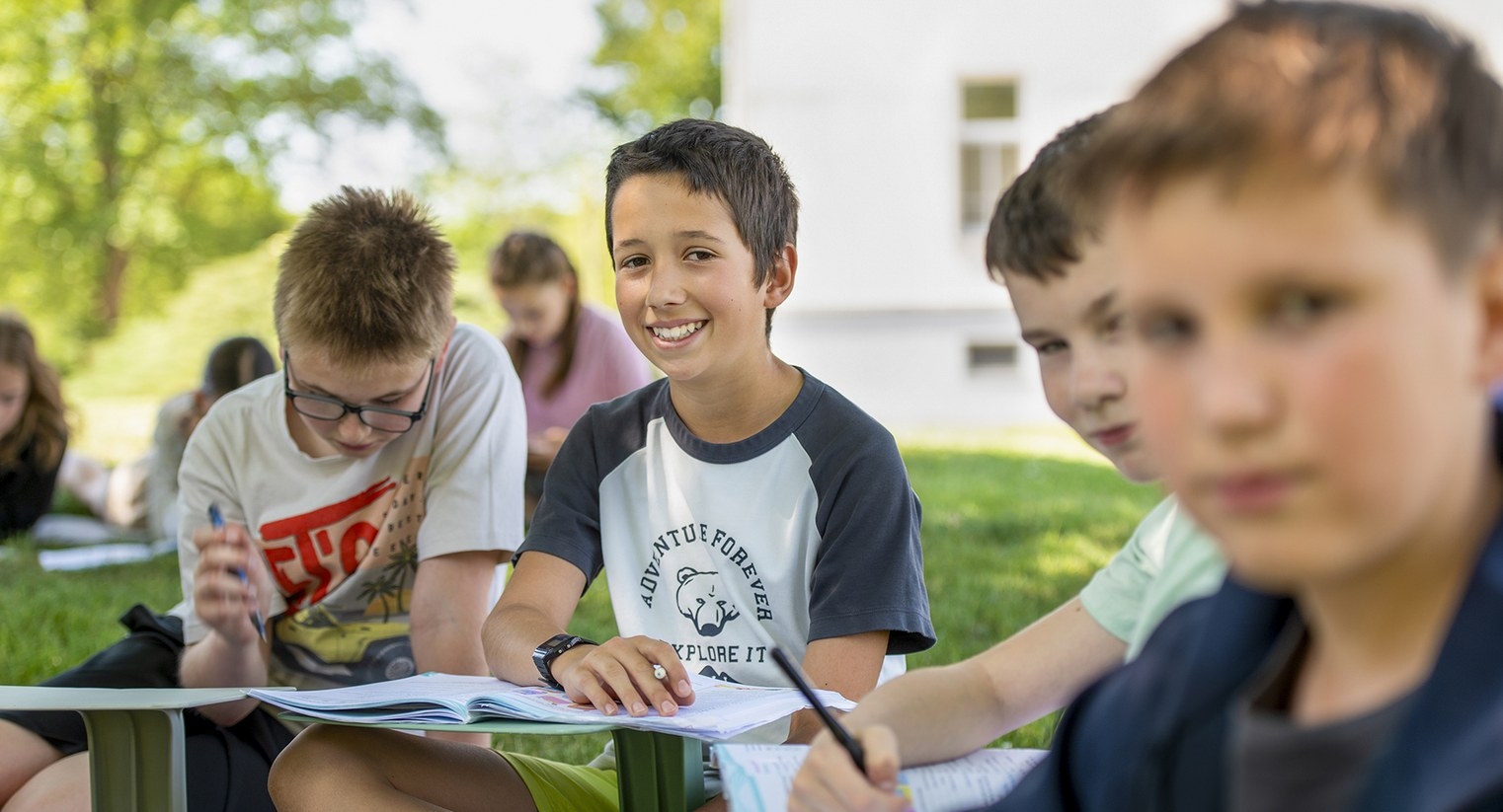 Usmívající se student při výuce venku na školní zahradě